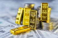 Kleine Goldbarren liegen auf Bargeld und an Münzen angelehnt
