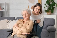 Seniorin im Rollstuhl und junge Frau haben gute Laune