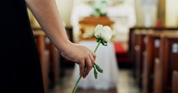 Frau mit weiße Rose vor einem Sarg. Das Bild zeigt eine Frau mit weiße Rose vor einem Sarg.